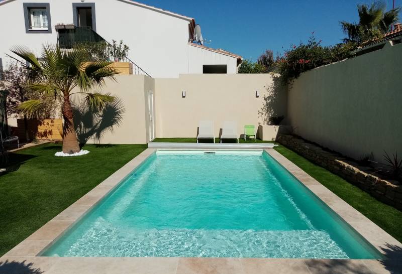Réalisation clé en main d'une piscine coque avec plage dans le Luberon. Intégration harmonieuse dans un petit jardin et équipement d'un volet de sécurité. Contactez Generale Piscines pour un devis gratuit.