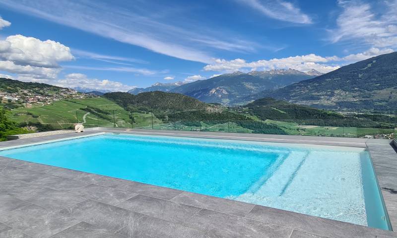 Piscine coque avec plage immergée (Media Plage) en finition claire, s'intégrant naturellement dans un environnement de campagne. L'expertise Generale Piscines dans le Vaucluse.